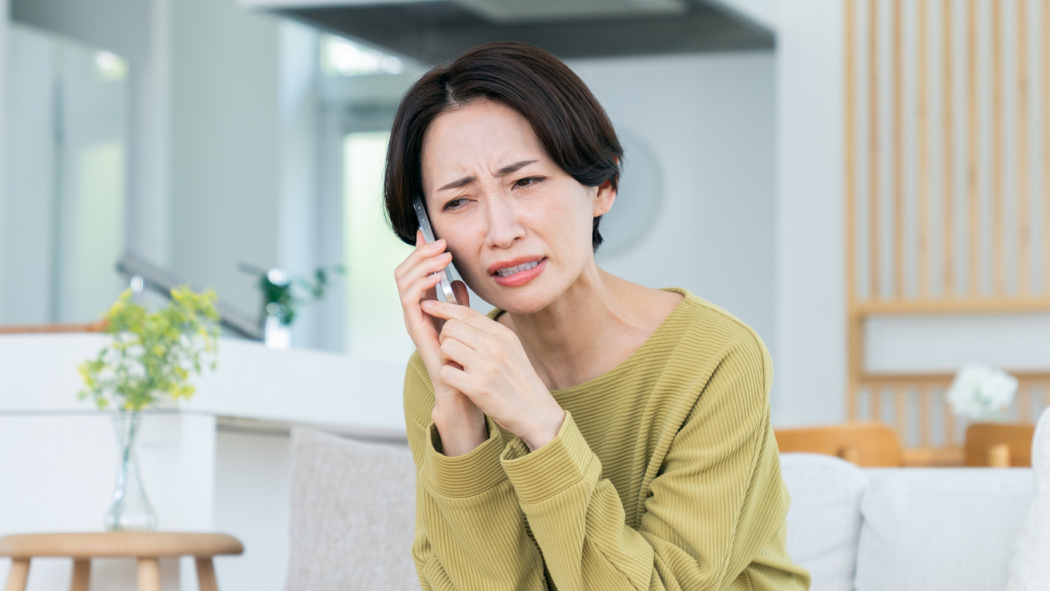 困った顔で電話をしている女性